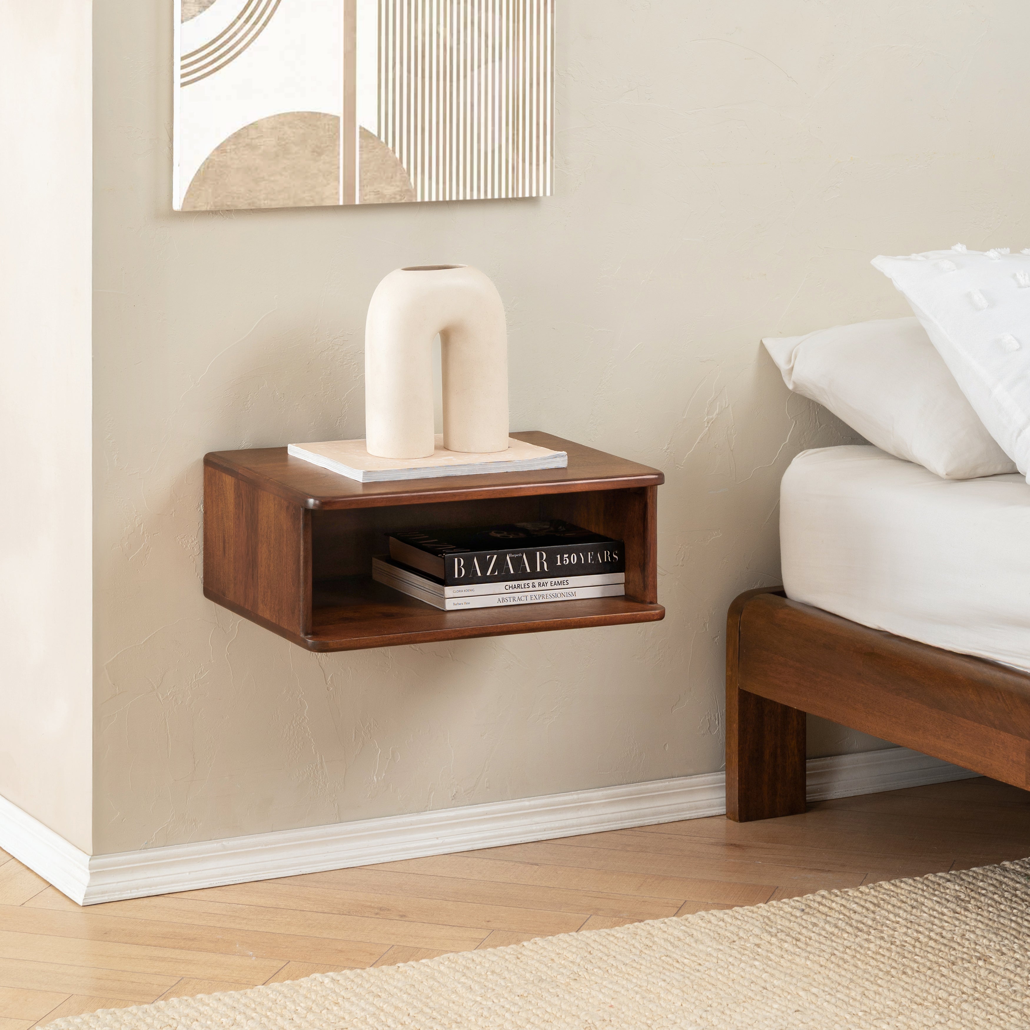 Wooden bedside table with decorative items next to a bed in a bedroom setting.